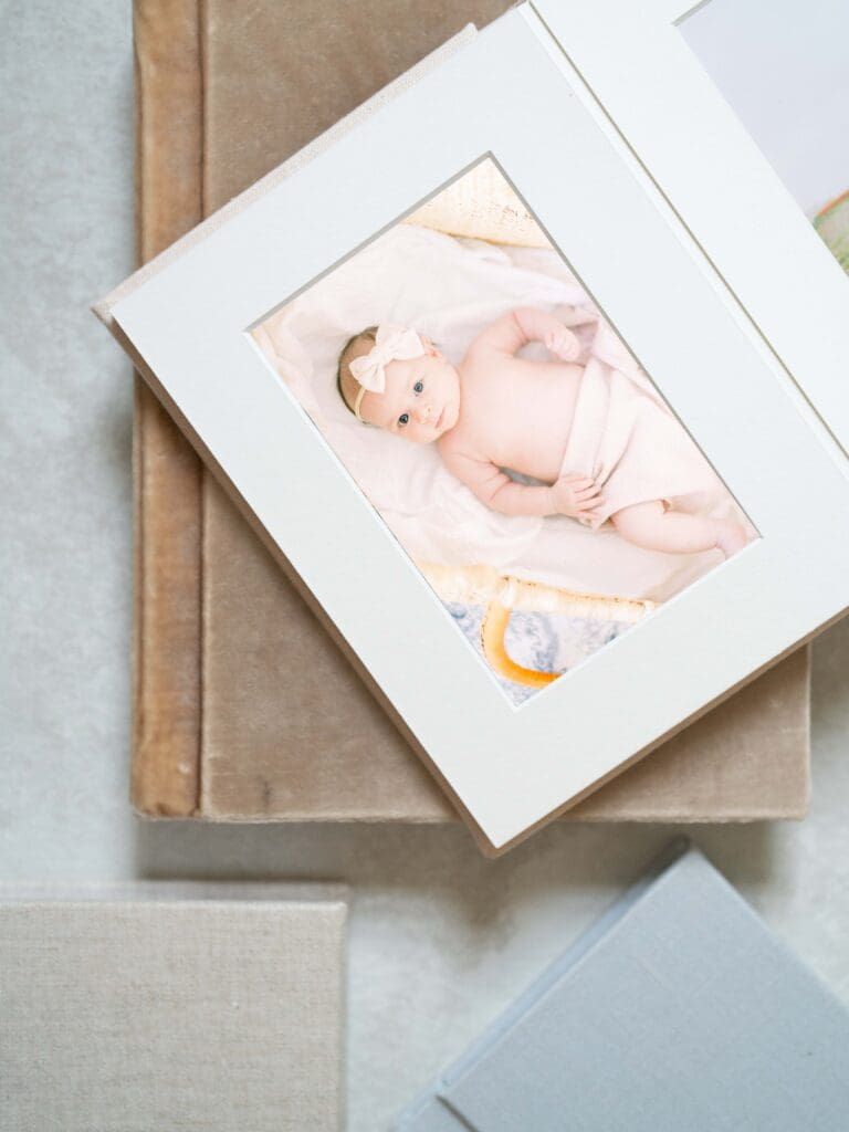 Matted photo album with image of baby girl in blanket with a bow headband from a newborn photography in Tampa.