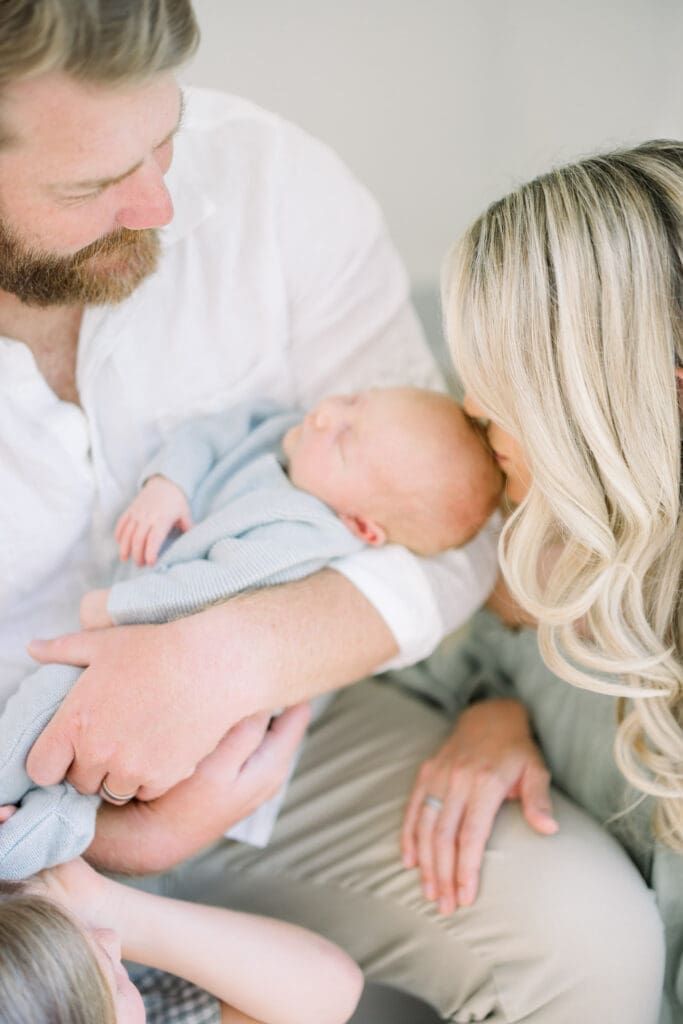 Dad holding baby while mom kissing baby's head for a Tampa newborn photography session.