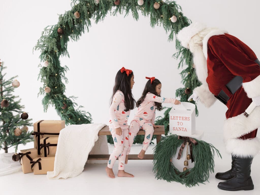 Sisters in pajamas putting letters in the mailbox during a photos with Santa.