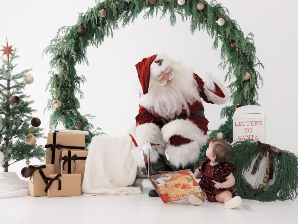 Santa reading a book to baby in for a Santa photoshoot in Tampa.