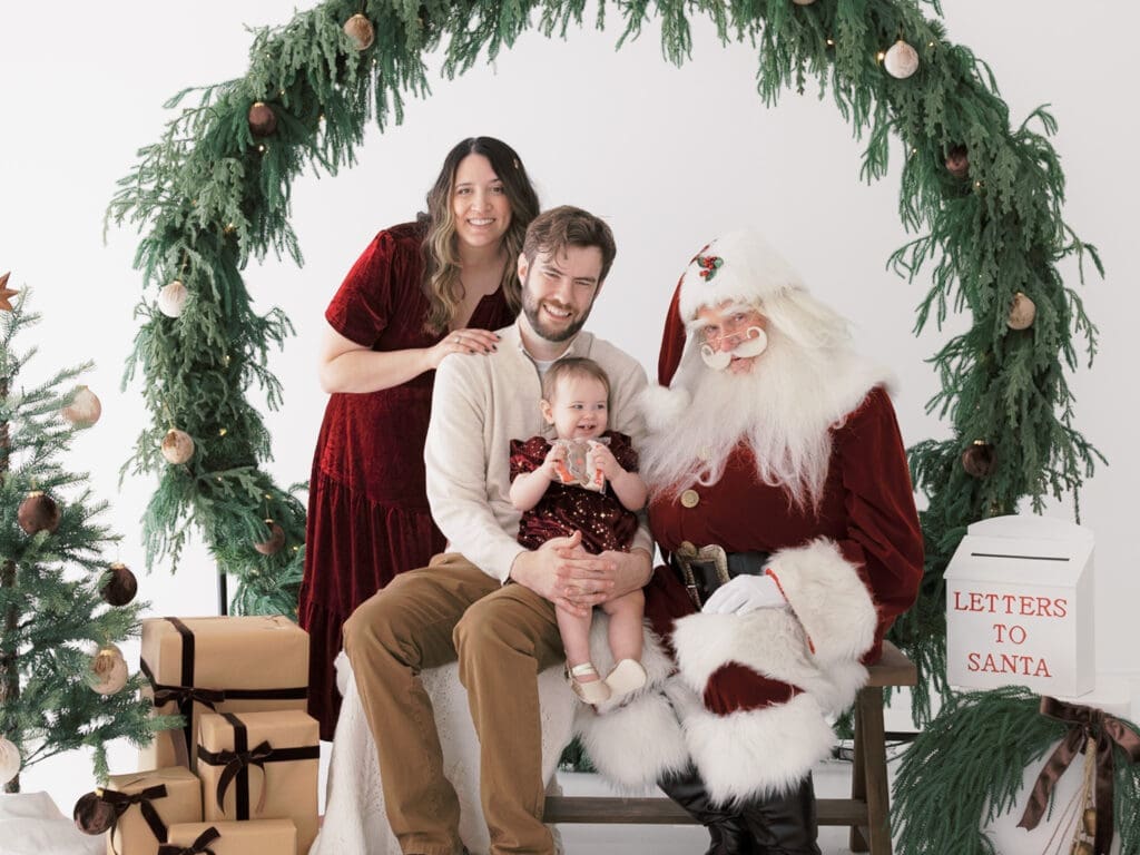 Family with baby smiling at Santa during her first Santa experience in Tampa.