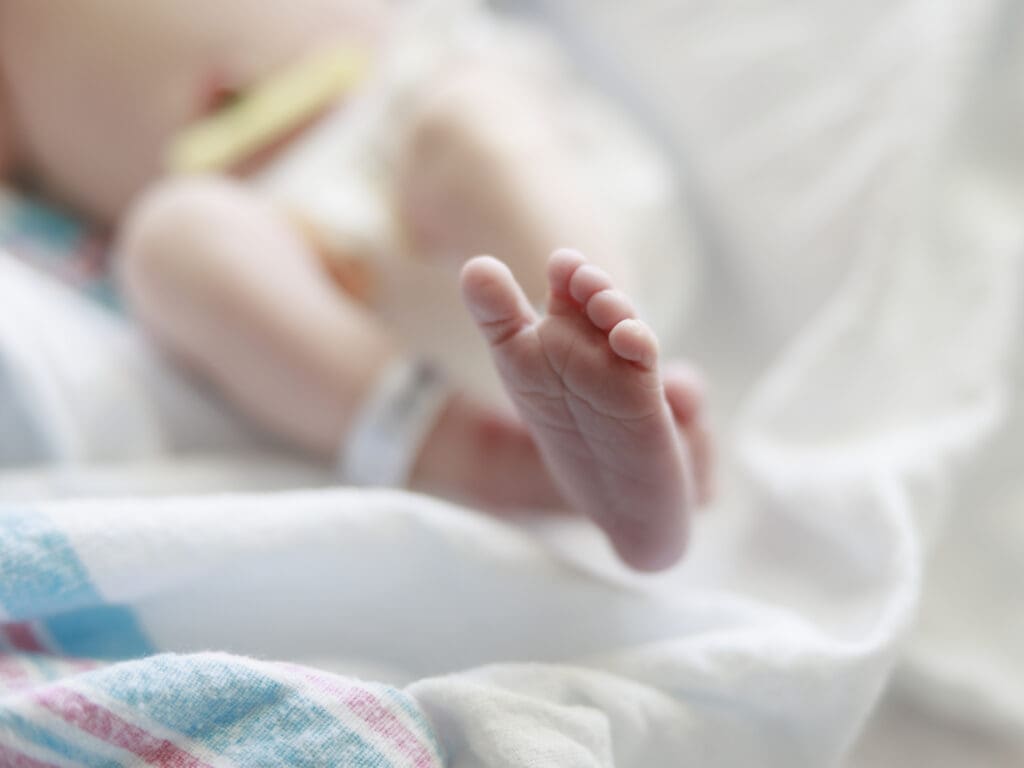 Newborn baby's foot in focus while laying on hospital blanket after a med-free birth in Tampa