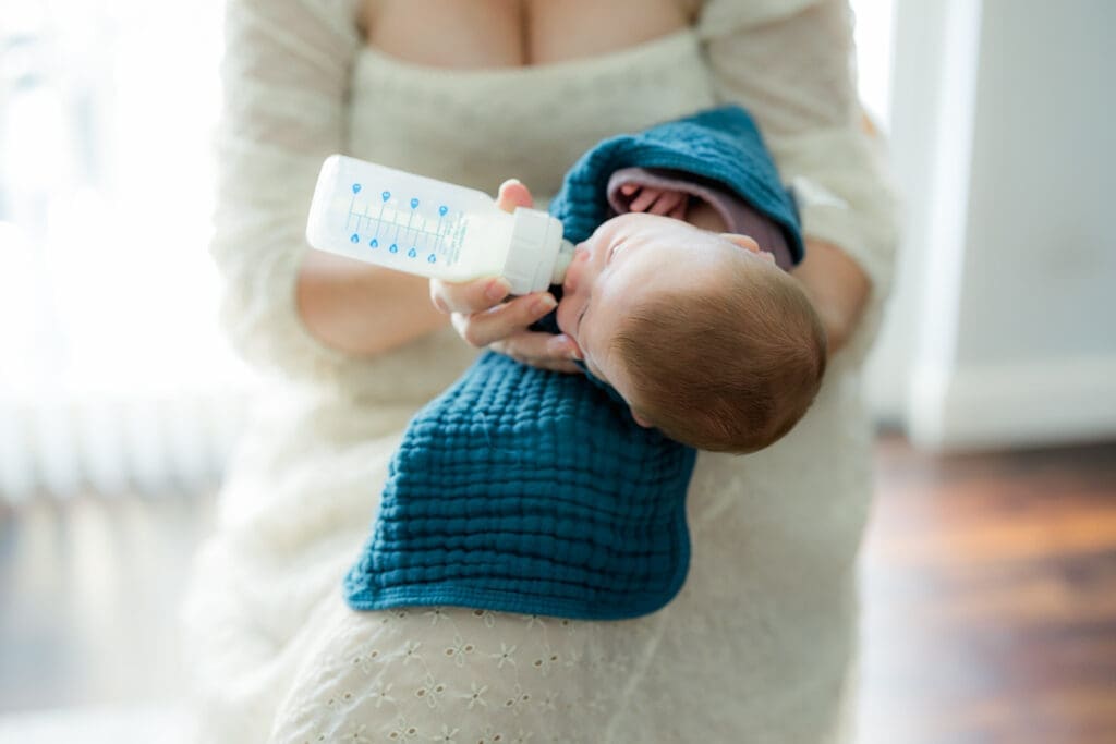 Parent feeding swaddled newborn baby in elevated side-lying position using gentle bottle feeding newborn baby tips in Tampa