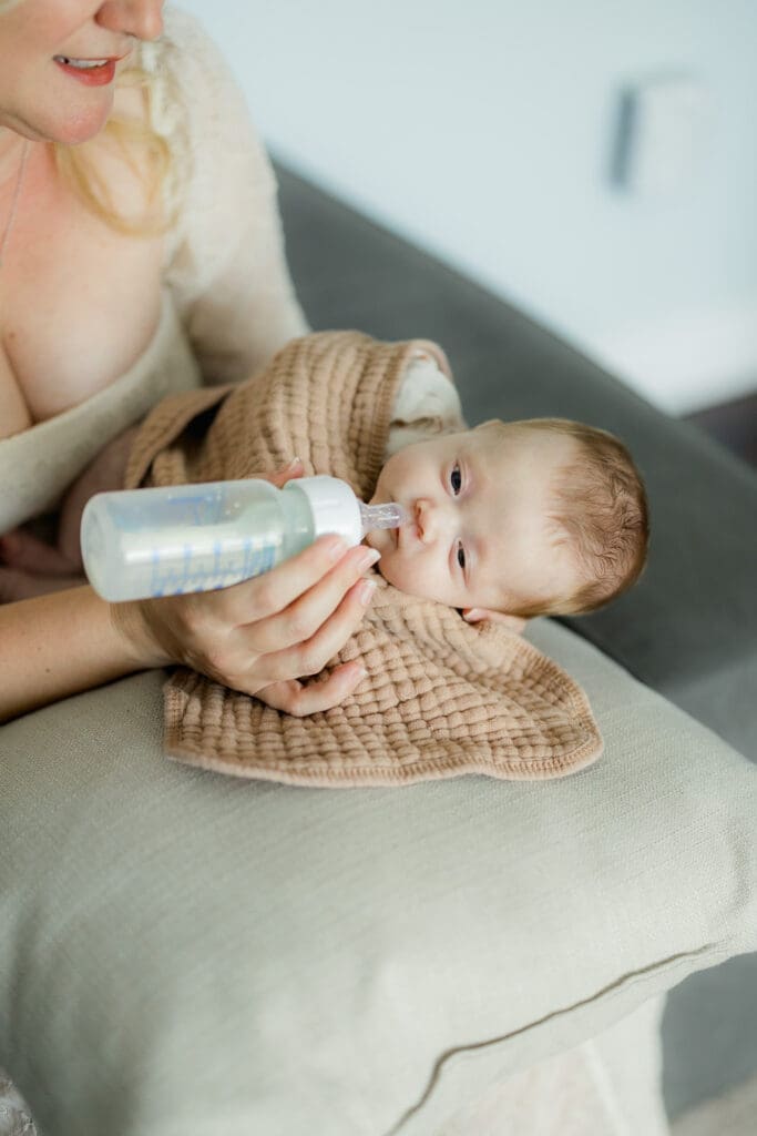 Mom offering newborn a slow flow nipple in elevated side-lying position – bottle feeding newborn baby tips in Tampa
