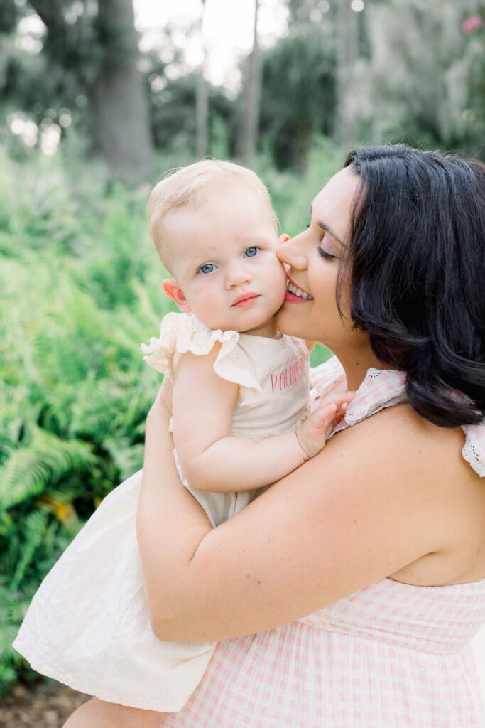 Mom with dark hair naturally pregnant holding daughter from IVF pregnancy in Sims Park for a Tampa Maternity Photography Session.