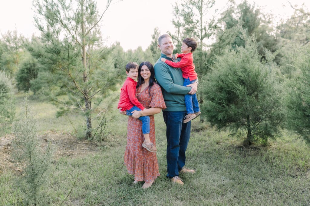 Couple holding sons in Blue Acres Christmas Tree Farm for Tampa Family Photography Mini Session.